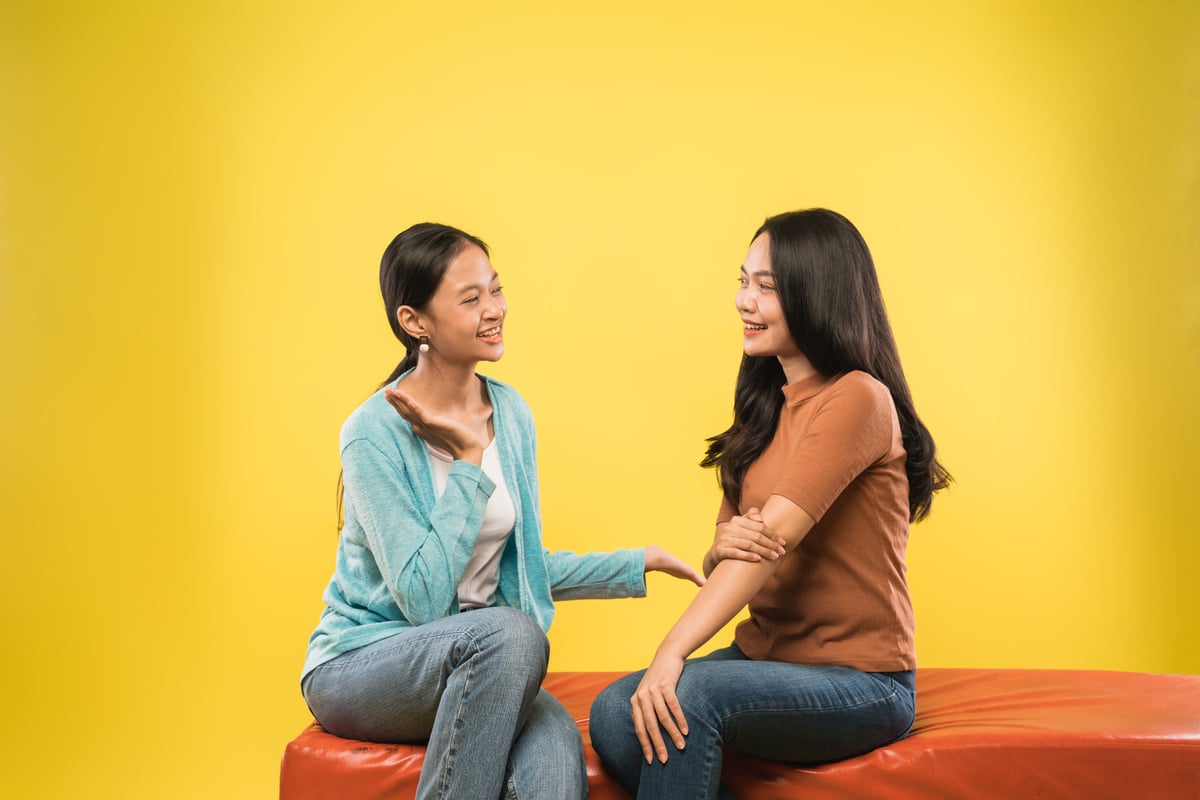 Two Beautiful Women Chatting While Sitting Together on the Couch